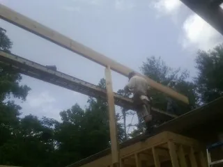 Carpenter setting a ridge beam over a new addition frame — Ice Dam Removal by Roofing Brothers in Greenfield