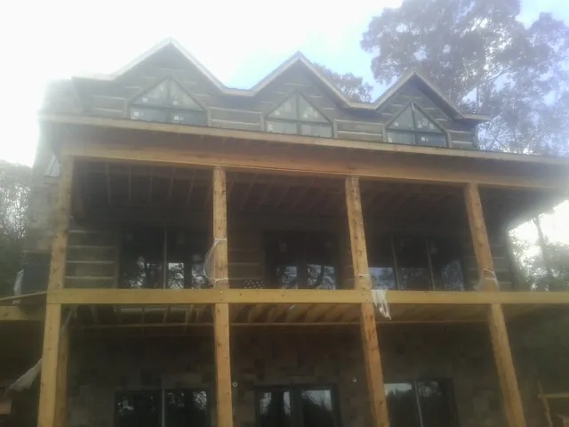 Dormers and porch framing on a large log home under construction — Roof Coating work by our crew in Greenfield