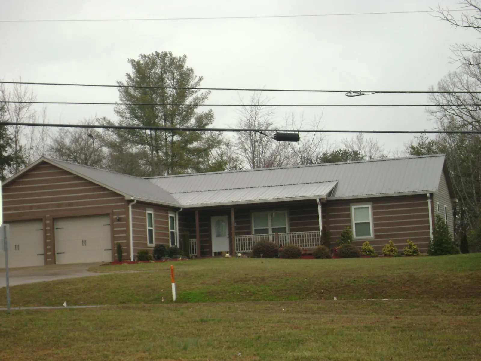 Gray metal roof on a log sided ranch home with a front porch in Greenfield